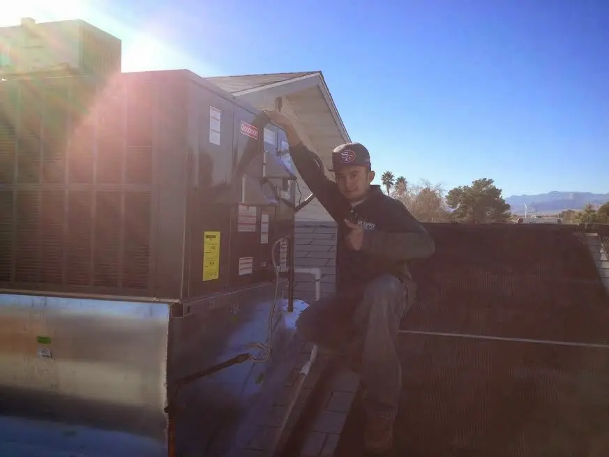 HVAC technician performing AC Tune-Up on a rooftop unit in Waukesha